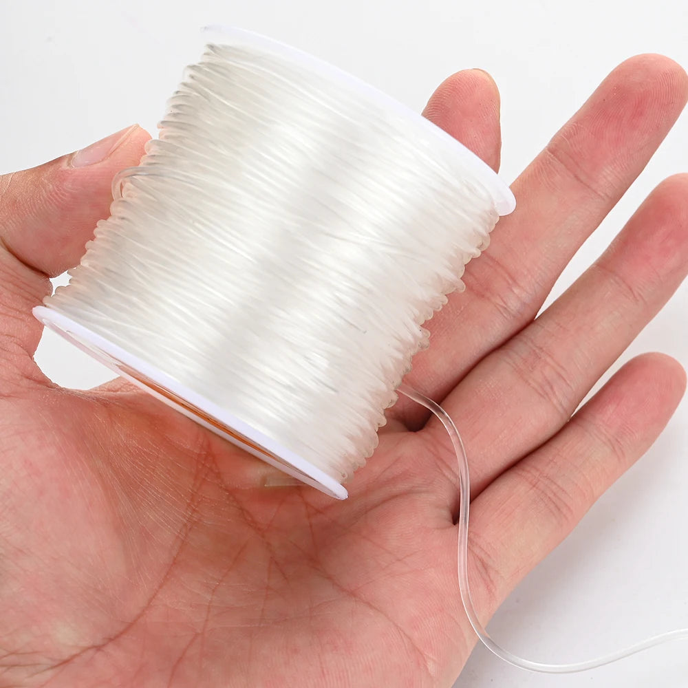 Transparent elastic thread spool with white cord, held by fingertips