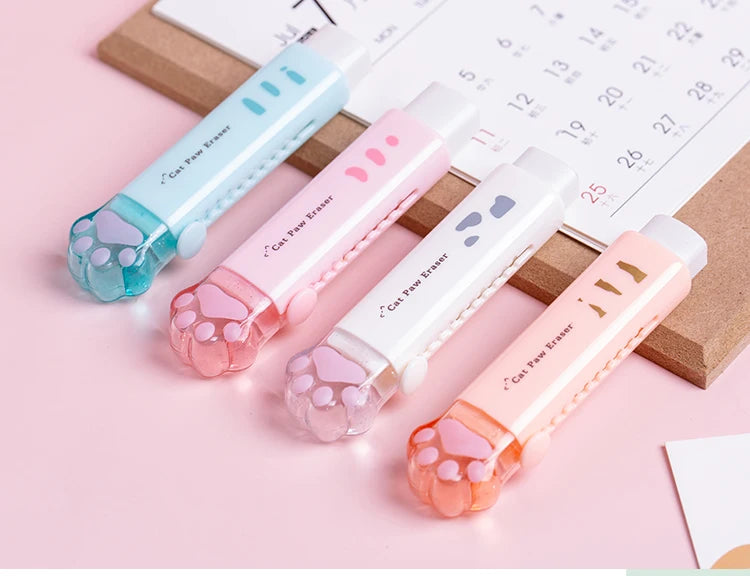 Retractable cat paw pencil erasers in blue, pink, white, and orange arranged near calendar