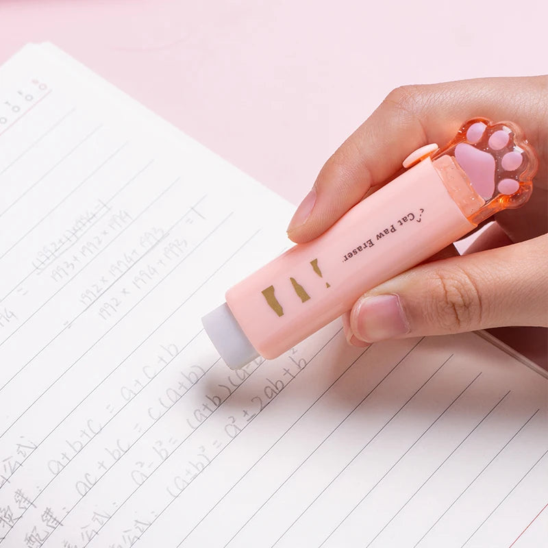 Retractable cat paw pencil eraser with orange claws, held above lined notes