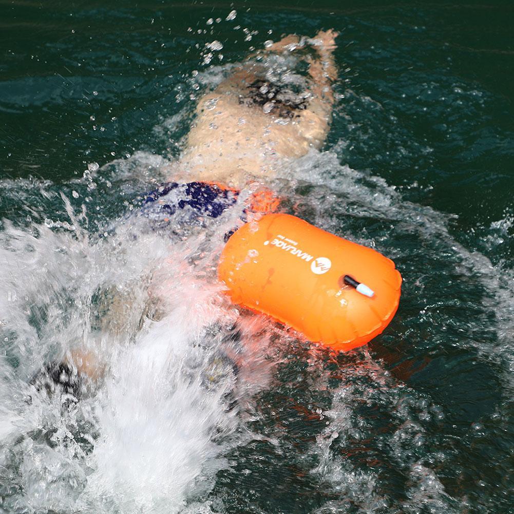 Inflatable swim buoy tow float, orange drifting in rippling open water splash