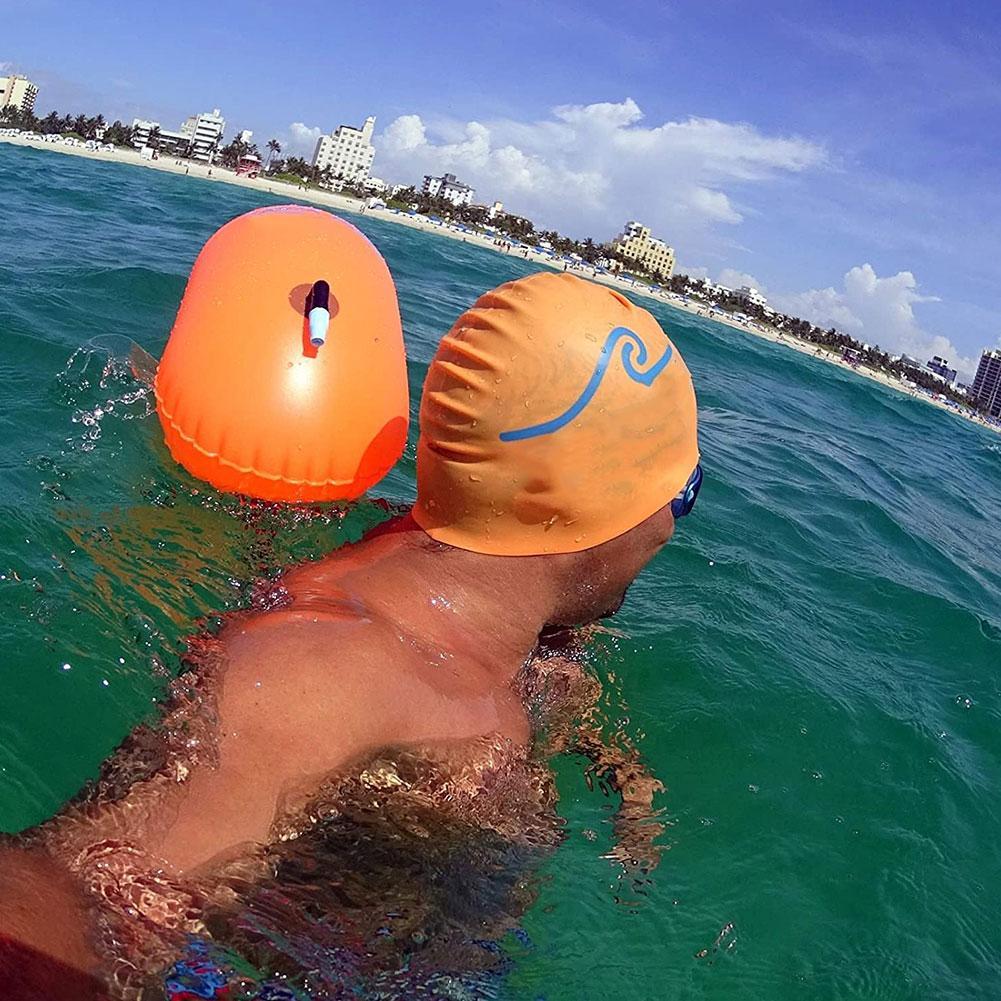 Inflatable orange swim buoy tow float with carry strap for open-water use