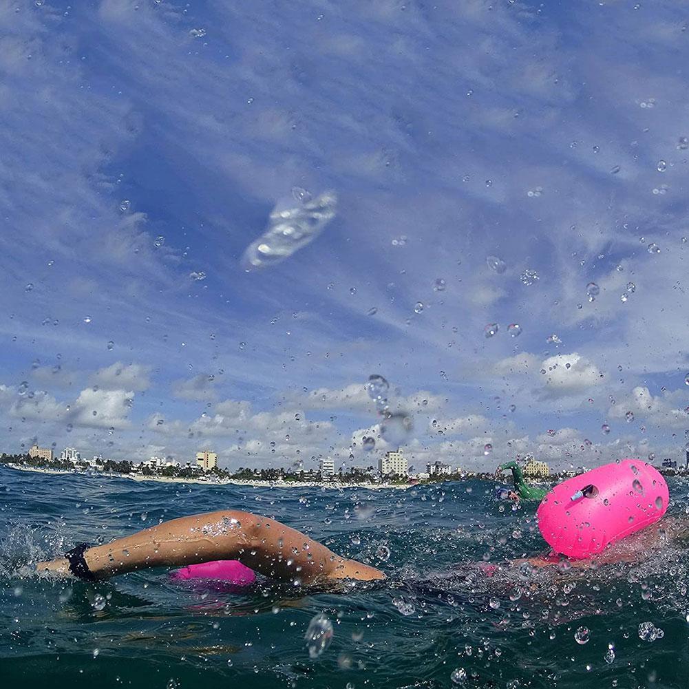 Rose pink inflatable swim buoy tow float floating beside swimmer in open water