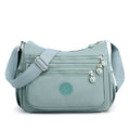 Light blue nylon crossbody bag front view with wide shoulder strap and front zip pockets
