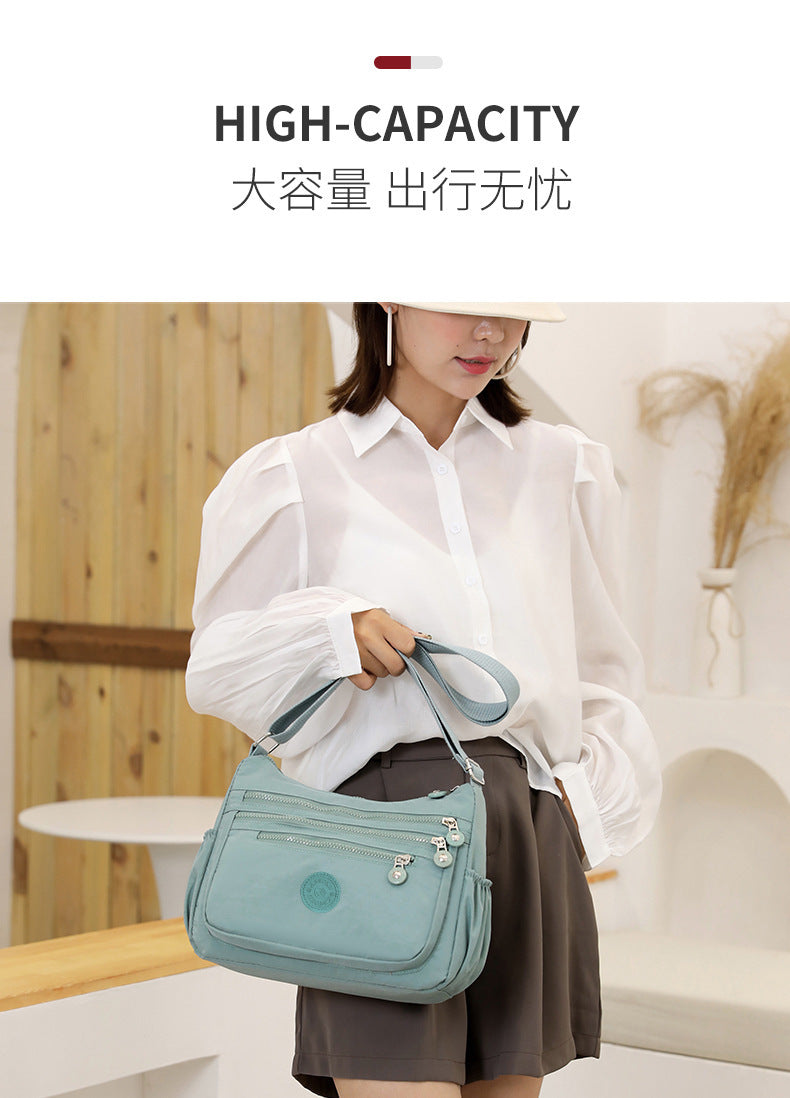 Lightweight multi-layer nylon shoulder bag, water-blue crossbody with zip compartments.
