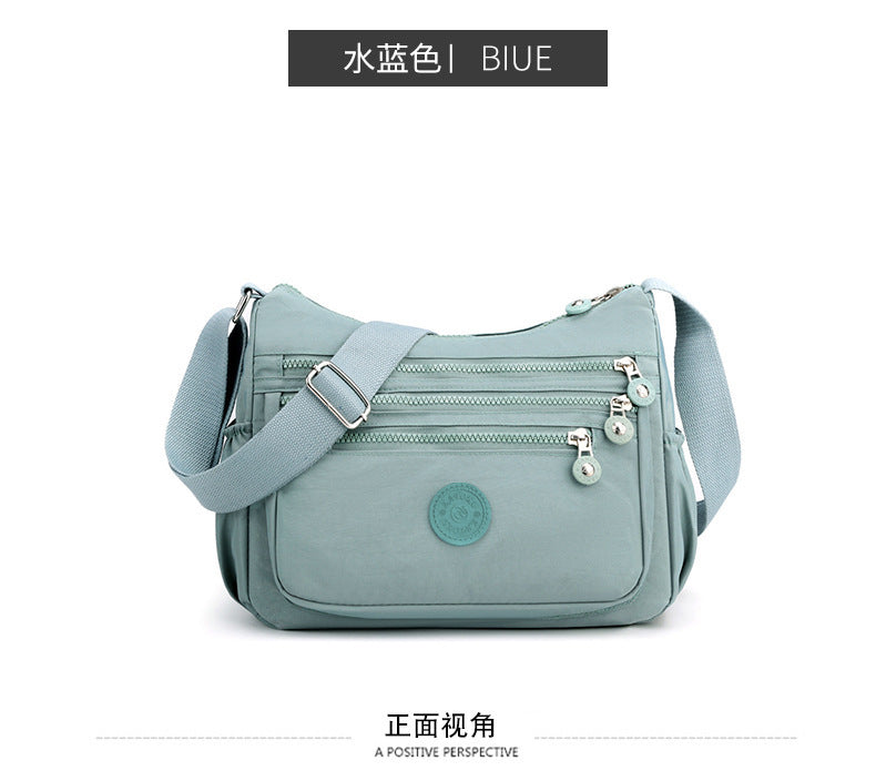Lightweight nylon crossbody bag in light blue with front pocket and dual zipper pulls