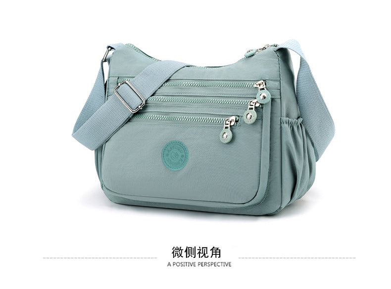 Lightweight nylon crossbody bag in light blue with multi-zip front pockets and shoulder strap