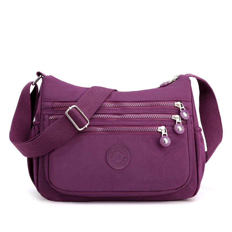 Purple nylon crossbody bag front view with front zip pockets and adjustable shoulder strap