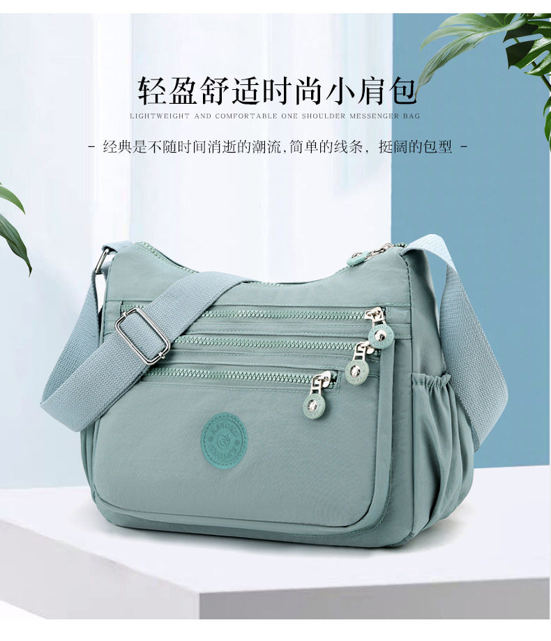 Lightweight multi-layer nylon shoulder bag, water-blue crossbody with zip pockets.