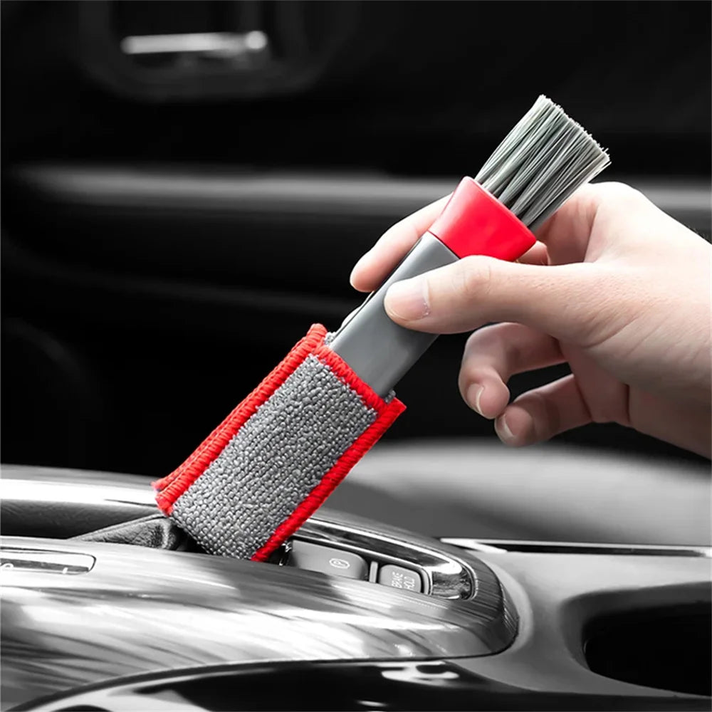 Car detail cleaning brush with gray bristles and red-edged gray pad, on console