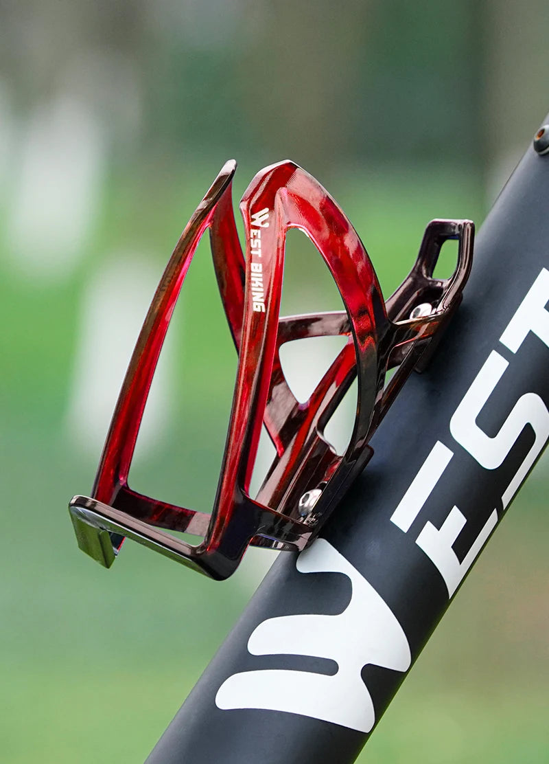Red bicycle water bottle cage mounted on a bike frame with bottle-holder opening