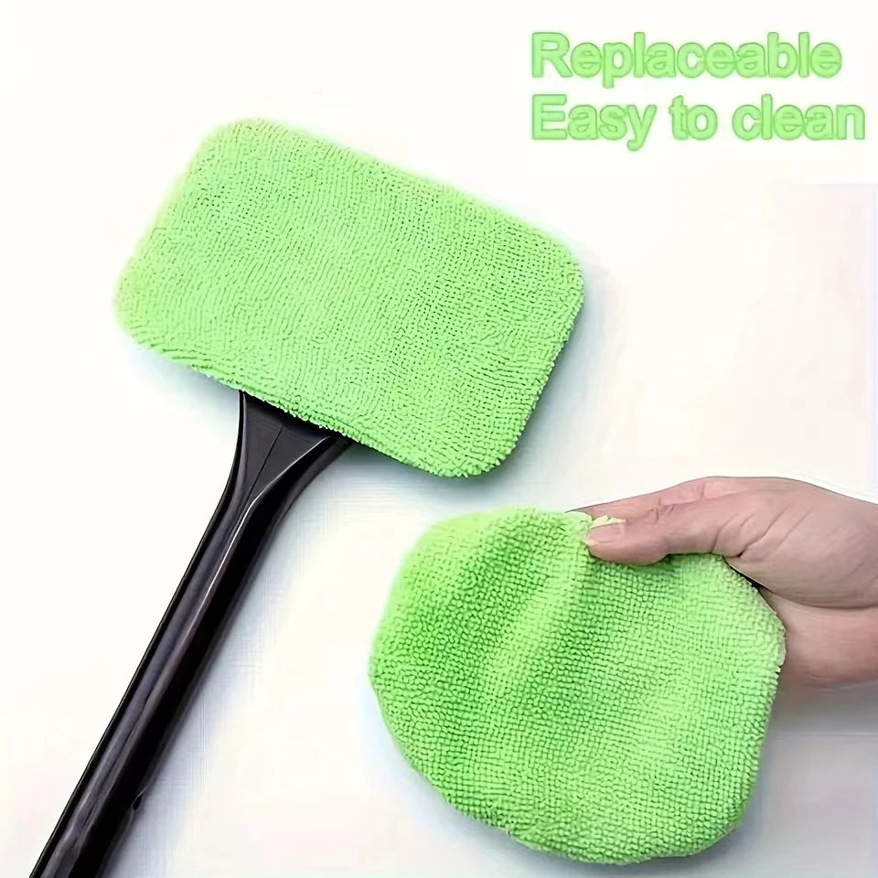Windshield cleaning brush with green microfiber pads, hand holds the brush