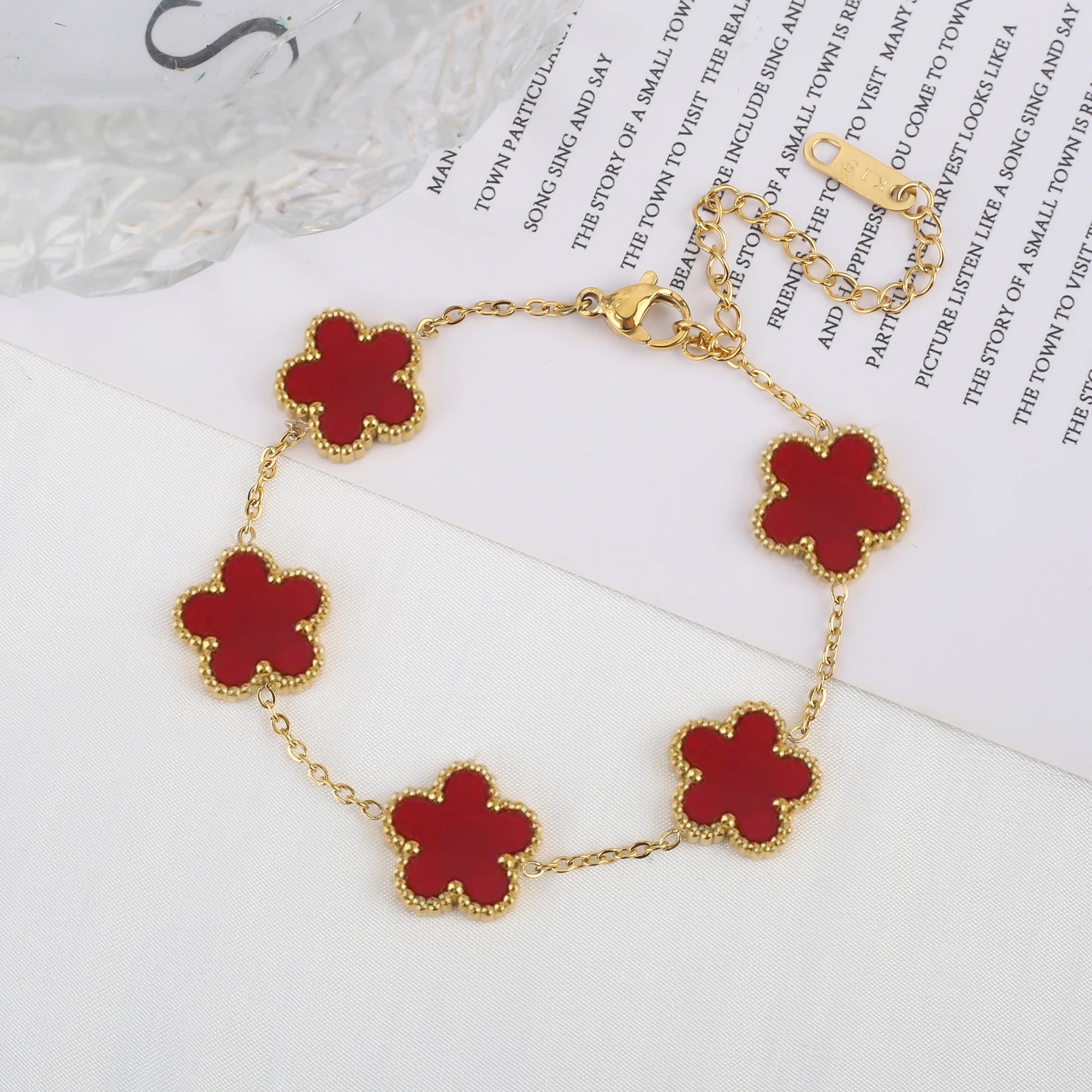 Adjustable gold bracelet with five red clover flower charms and linked chain
