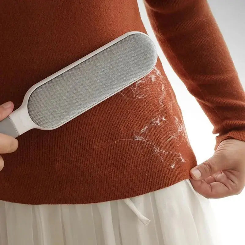 Gray lint brush with textured pad removing pet hair from fabric upholstery