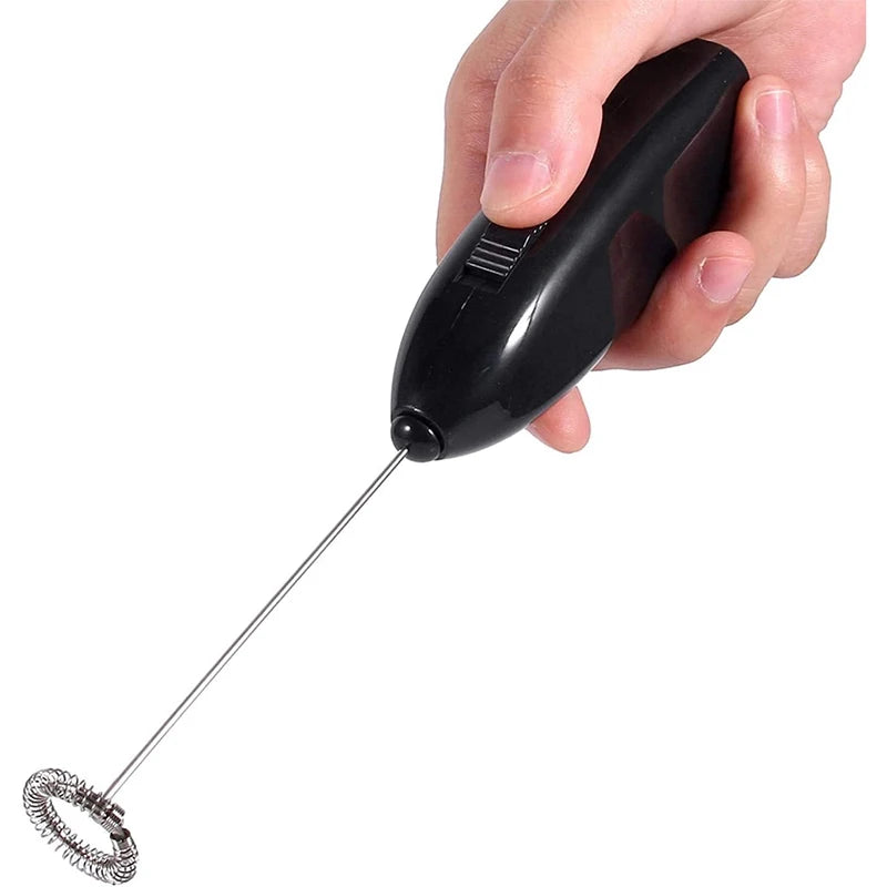 Handheld black mini milk frother with whisk beater, held in hand