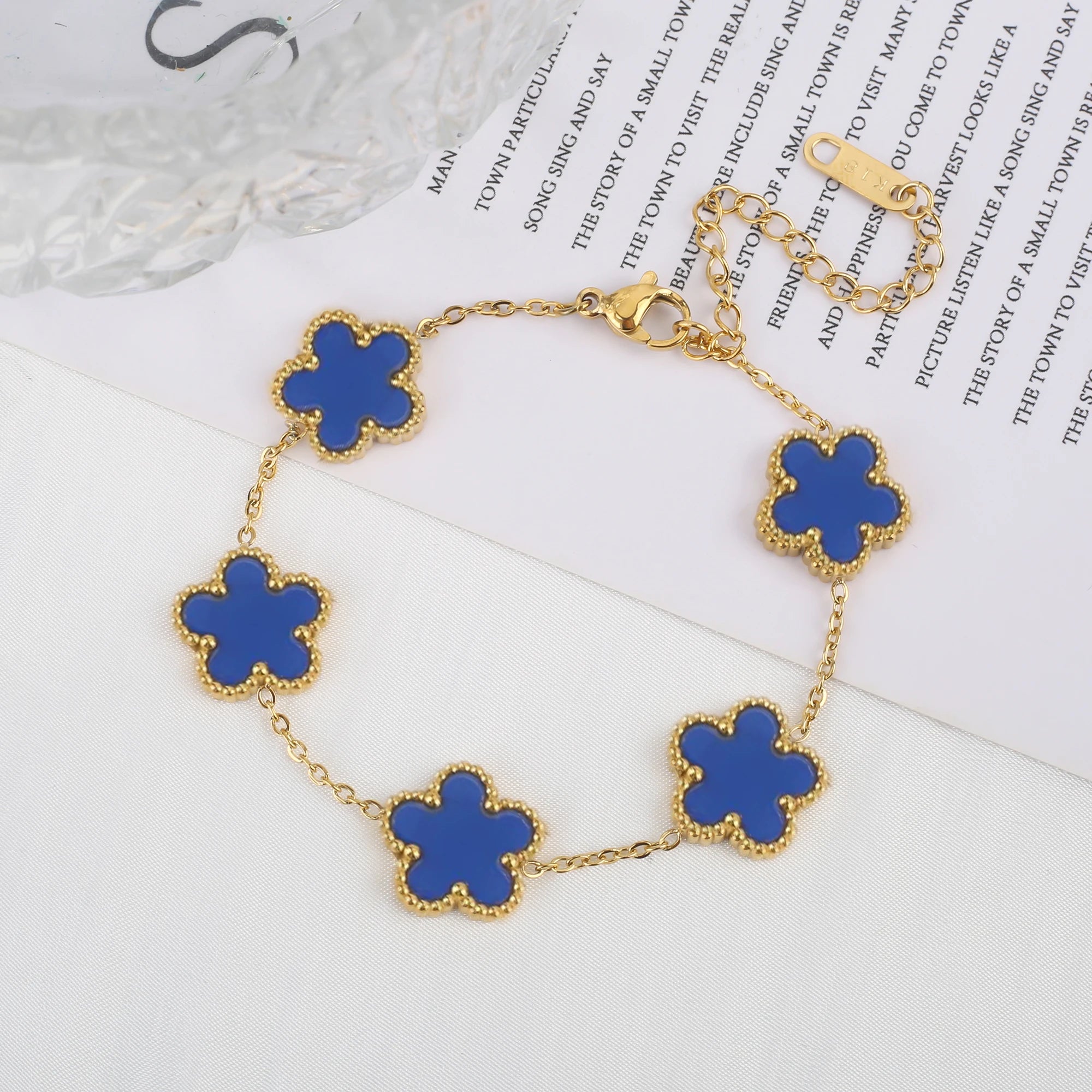 Adjustable gold bracelet with five blue clover flower charms and linked chain