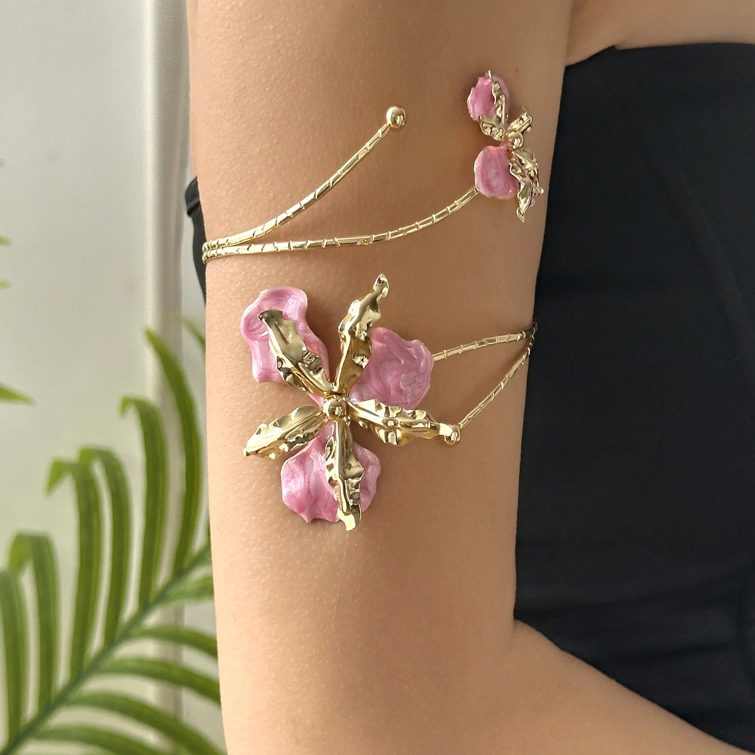 Gold and pink enamel flower arm bracelet with two chain cuffs on forearm
