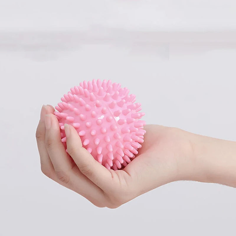 Pink spiked massage fascia ball held in one hand for muscle release