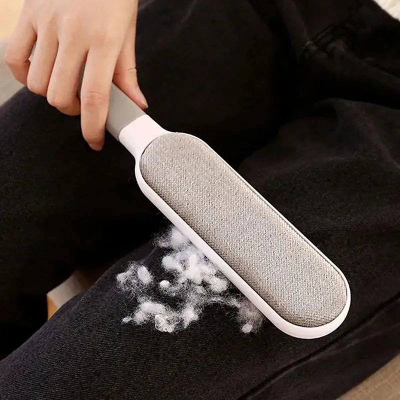 Gray textured lint brush removing pet hair from a dark fabric seat