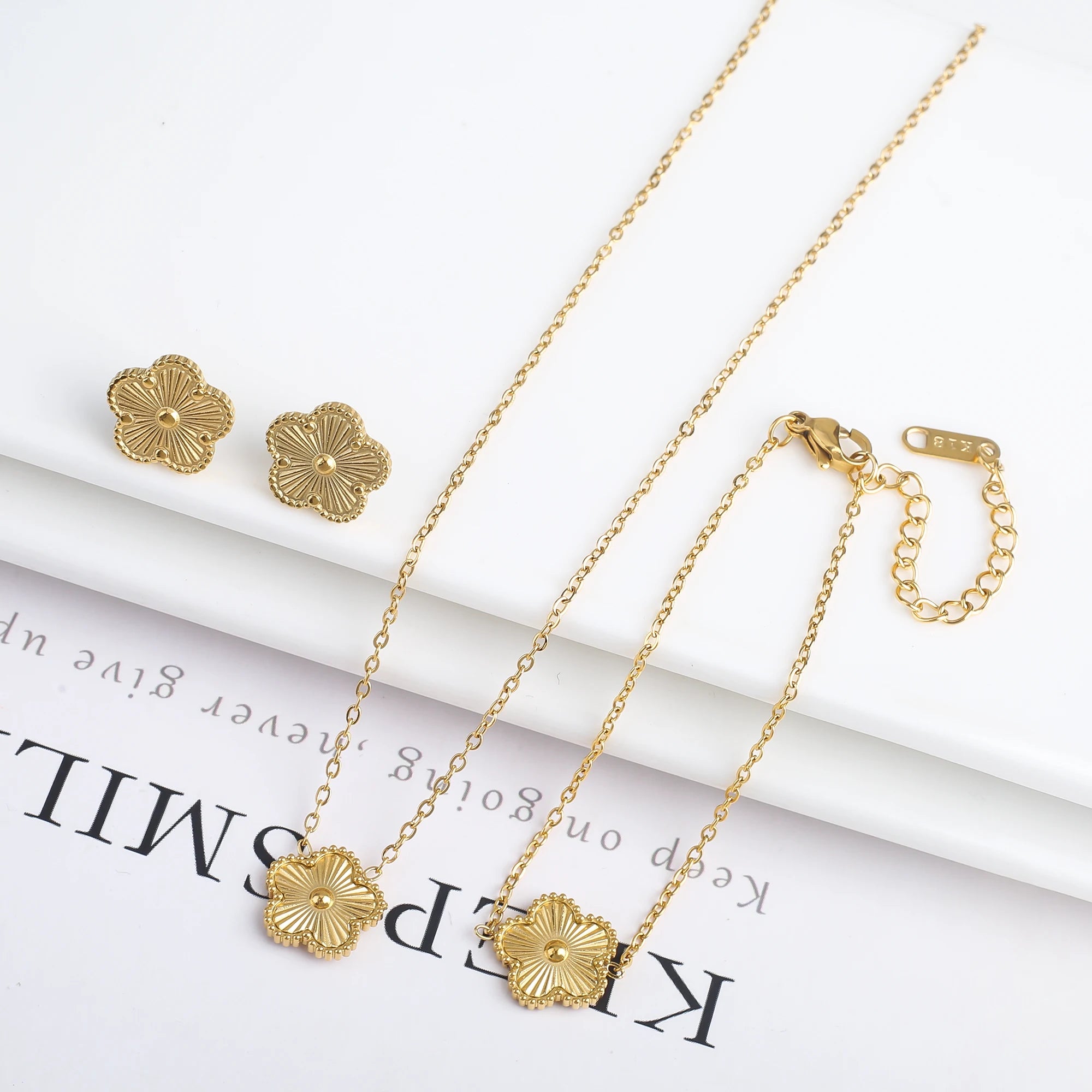 Three-piece clover jewelry set with five-leaf flower charms, gold tone necklace and hoop earrings