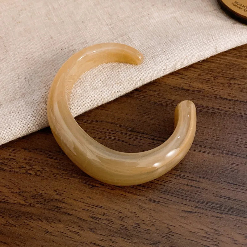 Amber/golden glossy open acrylic bangle with smooth curved open cuff design