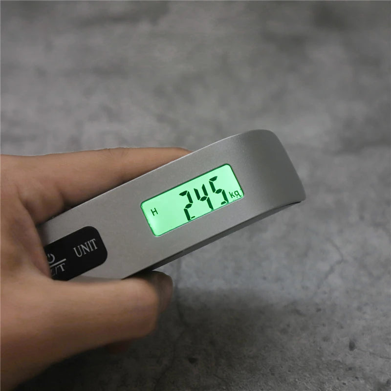 Hand holding portable digital luggage scale with green LCD weight reading