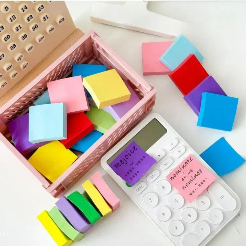 Set of colorful sticky notes in a tray with small memo flags and a calculator.