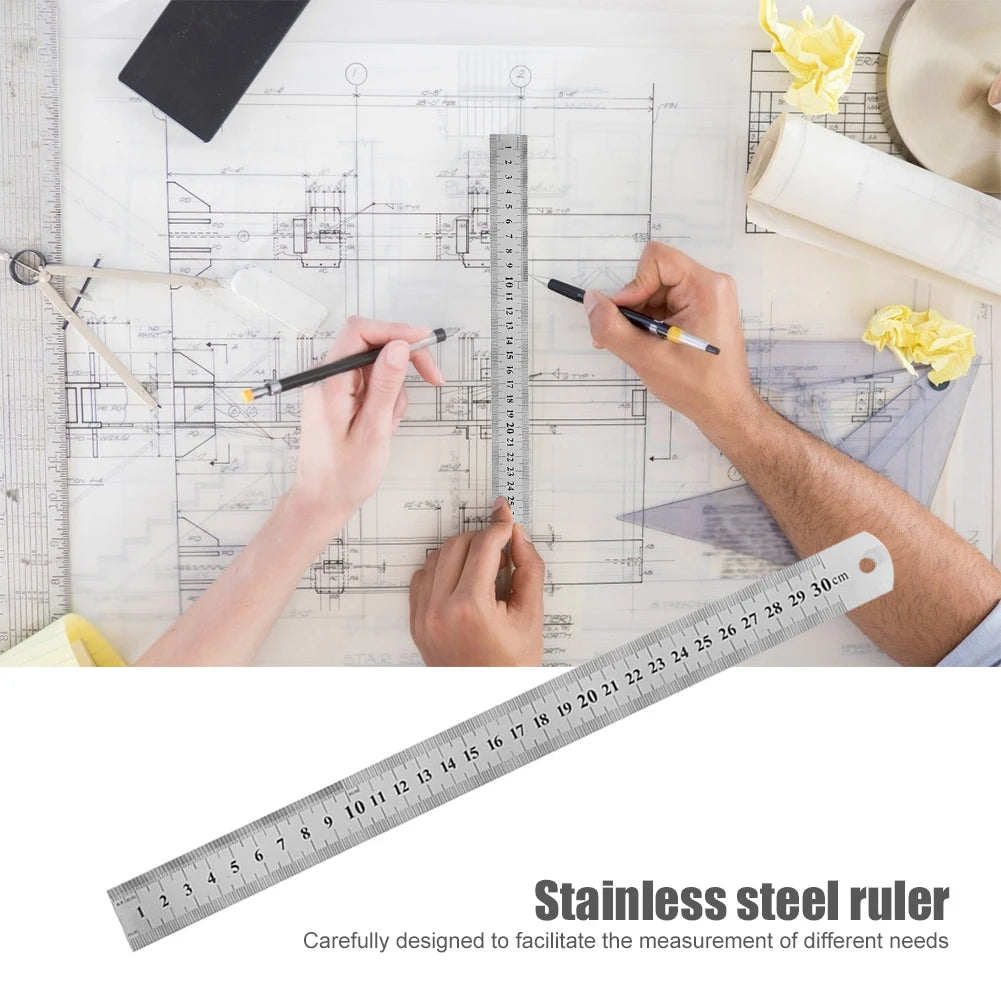 Stainless steel straight ruler across architectural drawing with measurement scale