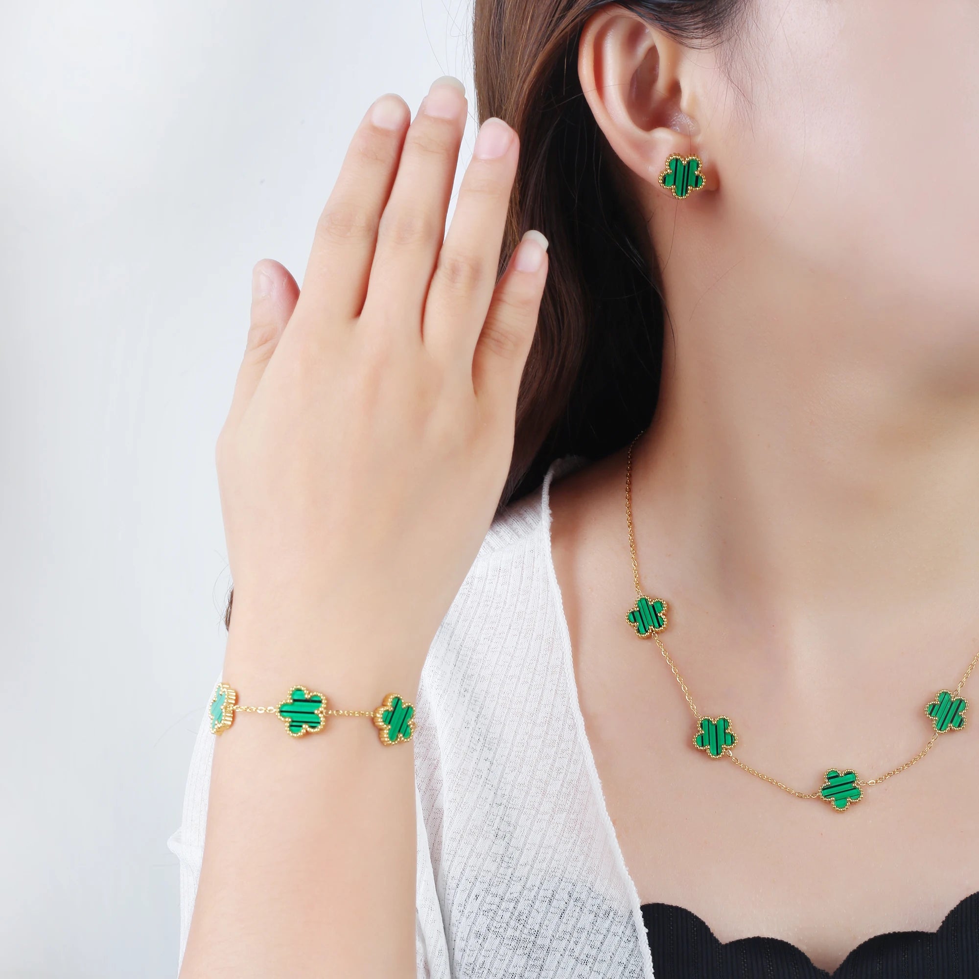 Gold-tone adjustable bracelet with green enamel four-leaf clover charms on wrist