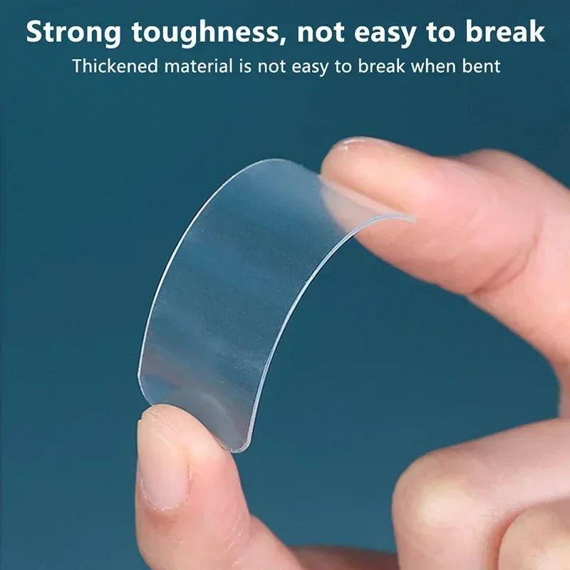 Transparent double-sided tape strip, bent and held by fingertips.