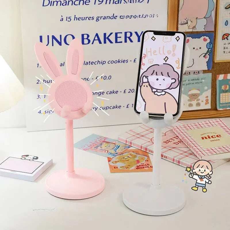 Pink rabbit phone stand with bunny ears and round mesh top, holding a smartphone