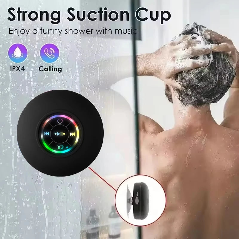 Black waterproof Bluetooth speaker with RGB light ring and suction-cup mount, shown near a shower stream