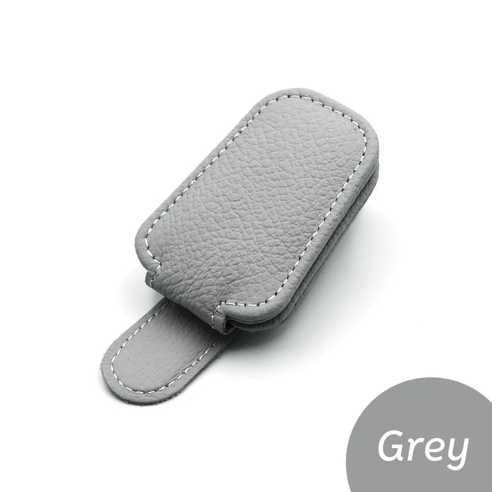 Gray car glasses clip holder with stitched leather-look finish and curved strap.