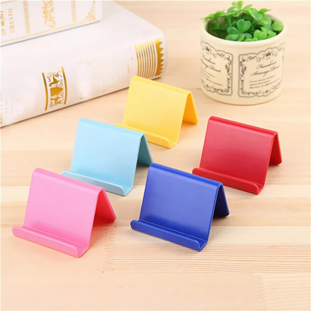 Colorful plastic phone holder stands in blue, pink, yellow, and red, foldable