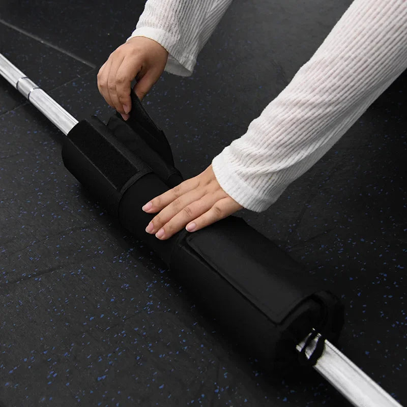 Black foam bar pad being placed on a barbell, hands adjusting for fit