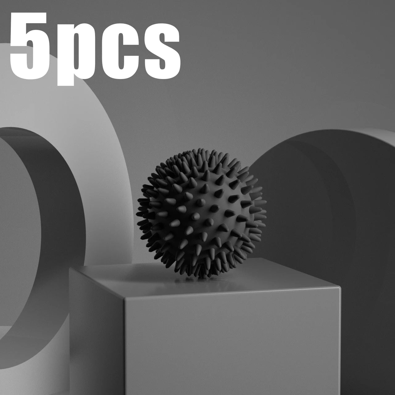 Black spiky fascia massage ball for muscle relaxation, centered on a gray block