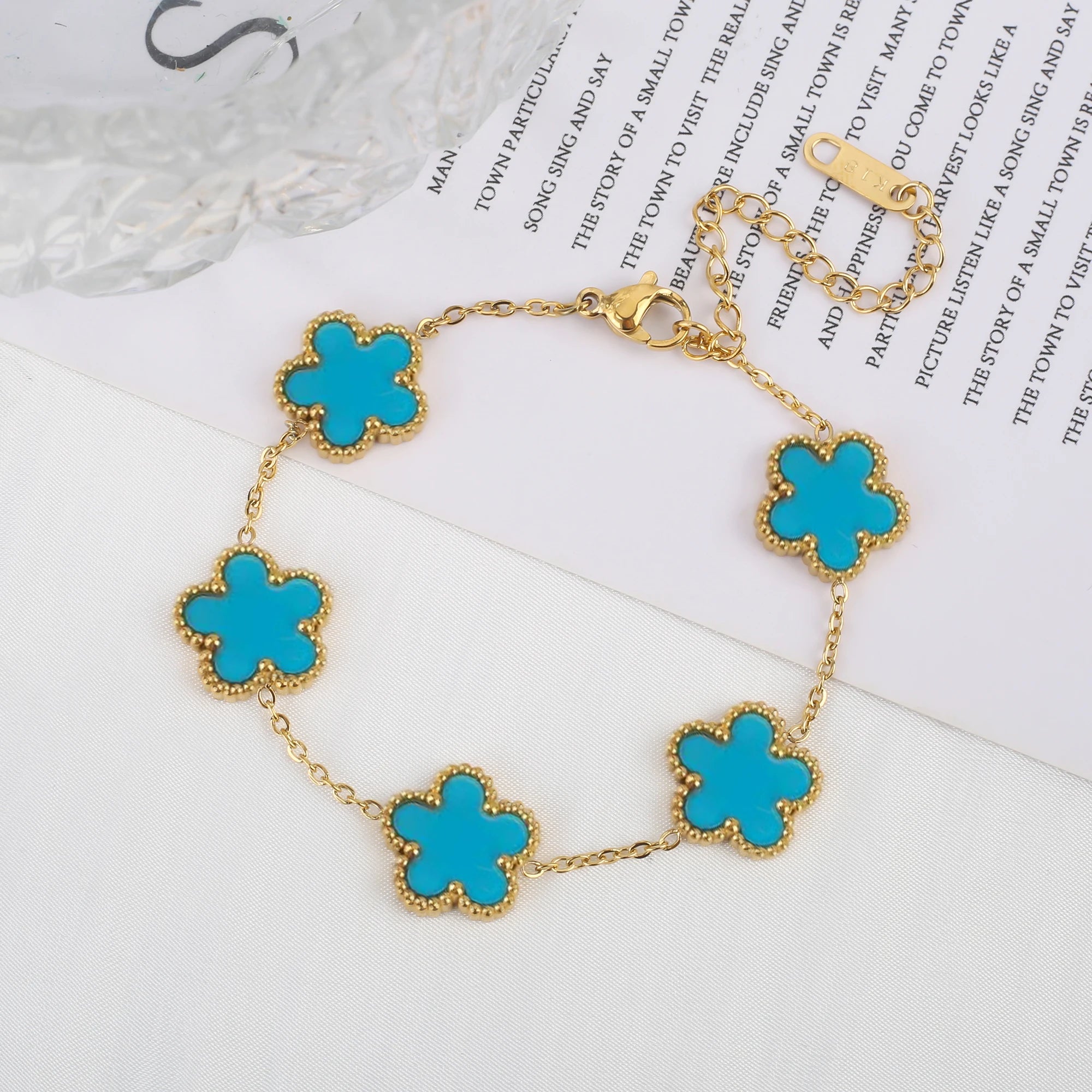 Adjustable gold-tone clover charm bracelet with blue enamel four-leaf pendants