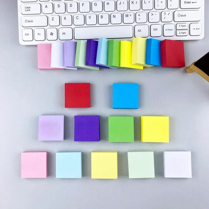 Neon square sticky note pads in mixed colors arranged in rows under a keyboard.