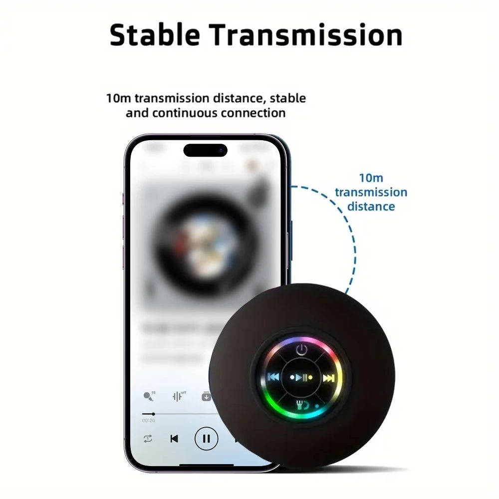 Black portable Bluetooth speaker with RGB light ring next to a smartphone, compact round design