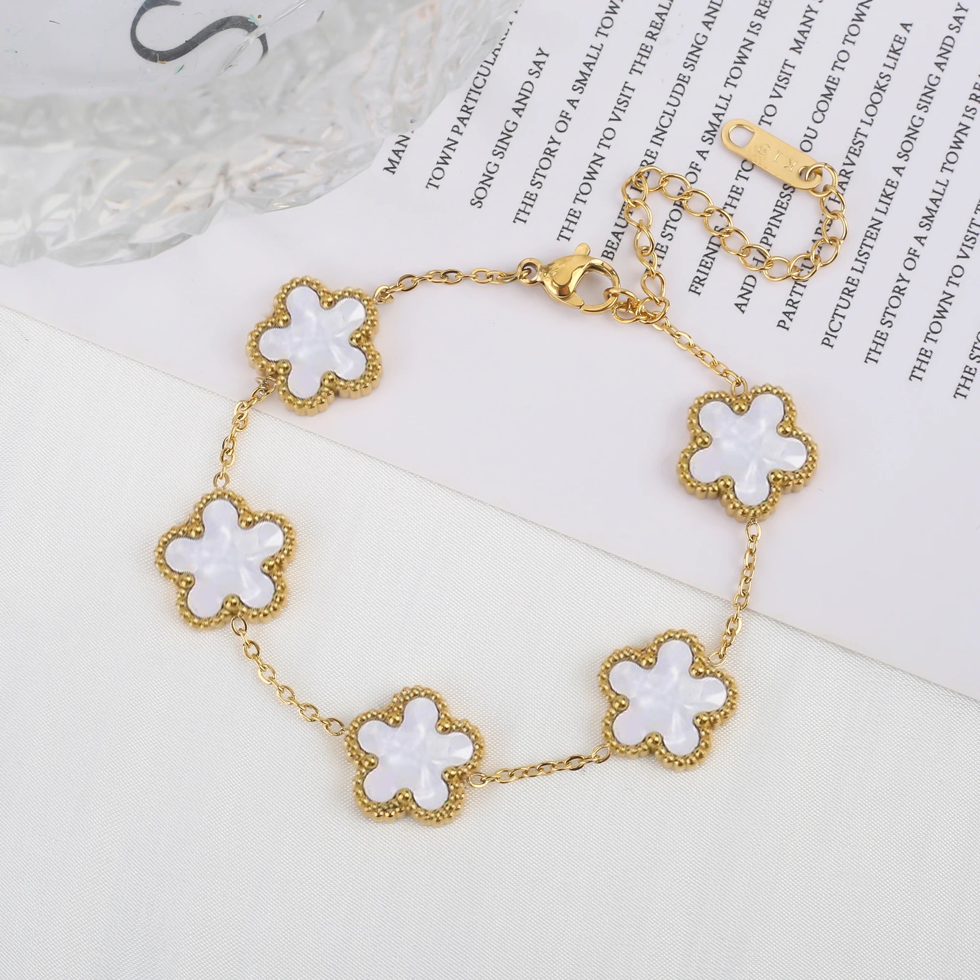 Adjustable gold bracelet with five white clover flower charms and linked chain