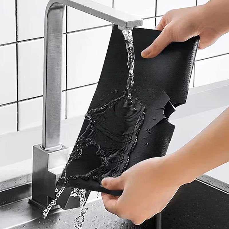 Black stove protector pad liner being rinsed, water pouring through the material