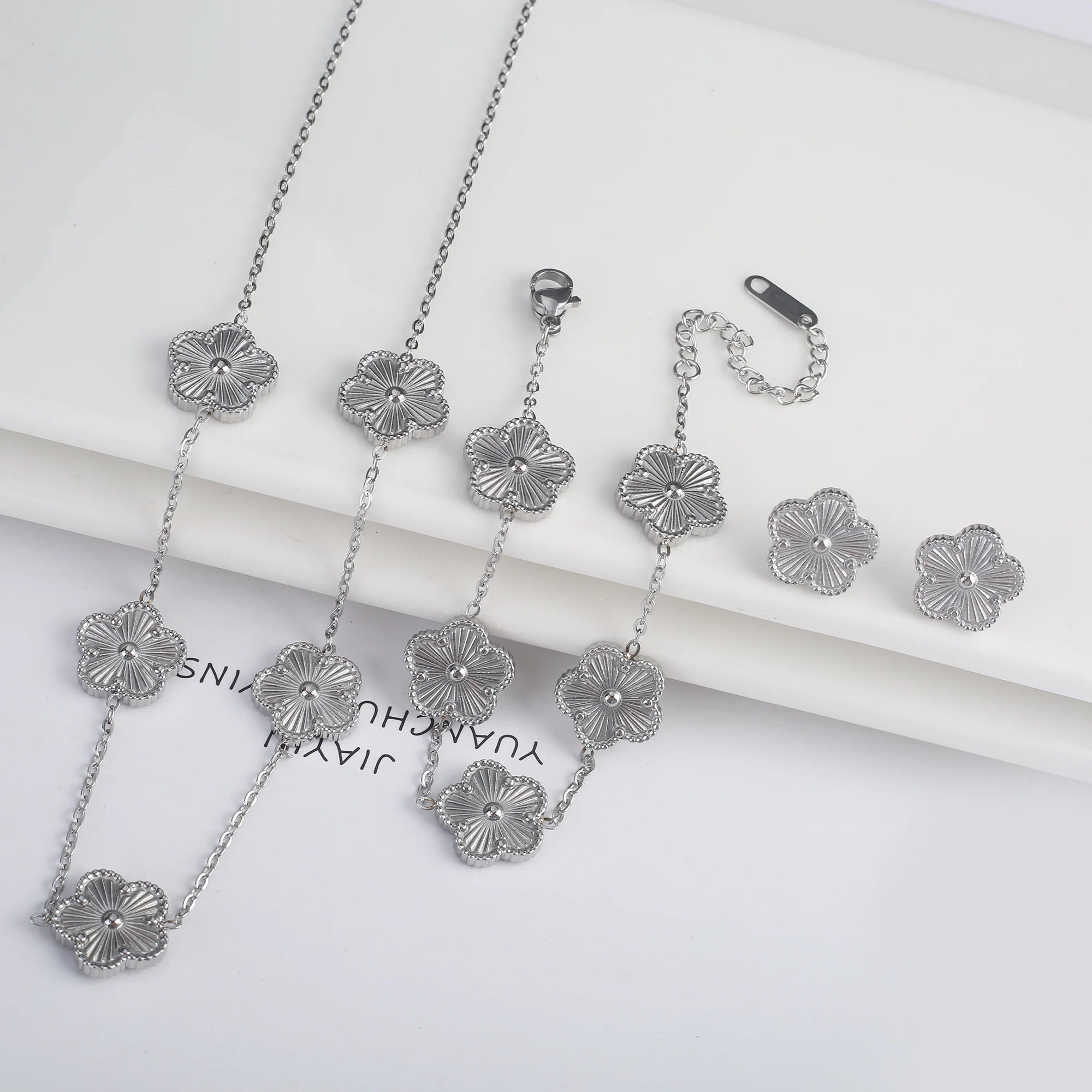Three-piece clover jewelry set with five-leaf flower charms, silver tone necklaces and dangling earrings