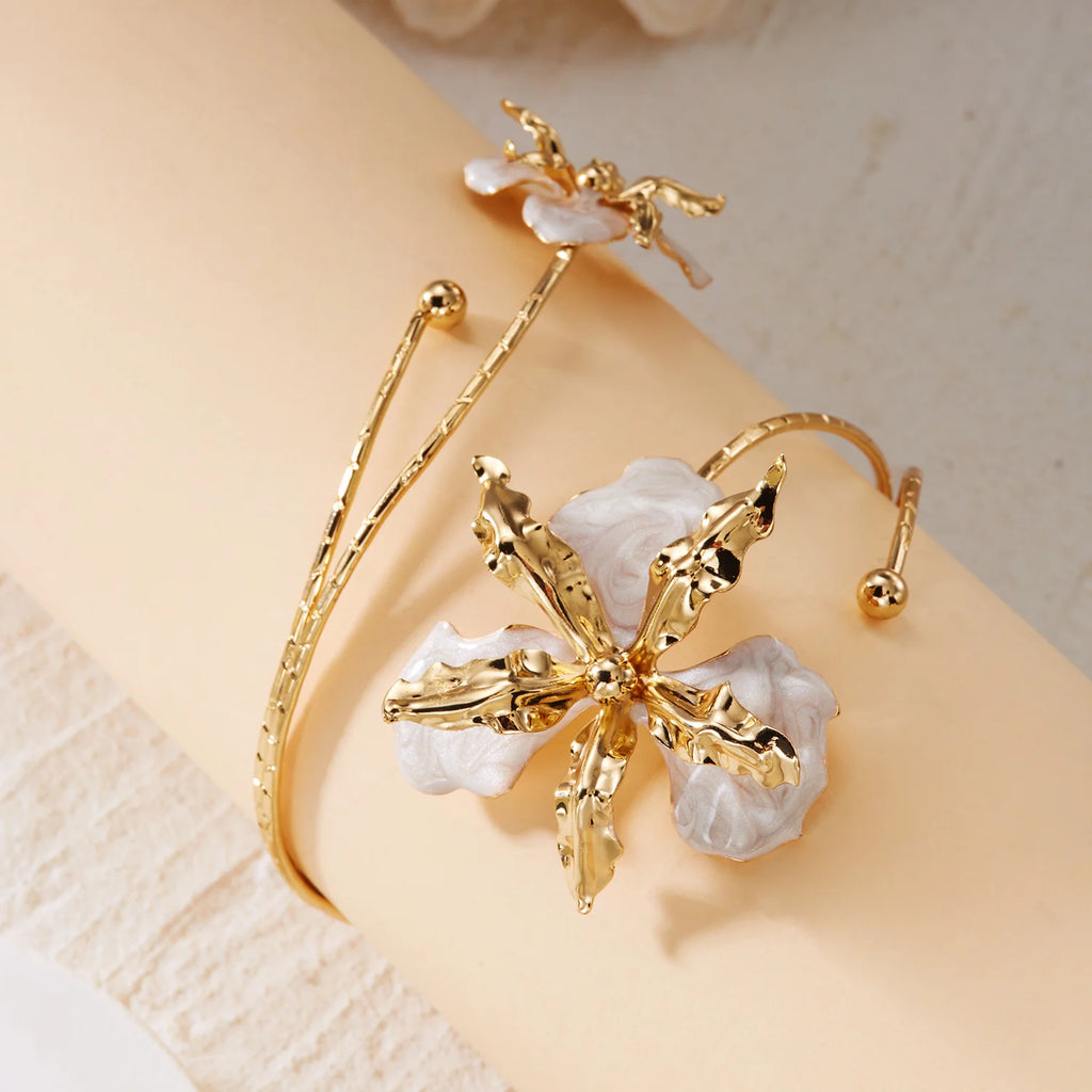 Gold-tone floral arm bracelet with open cuff and white enamel flower cluster.