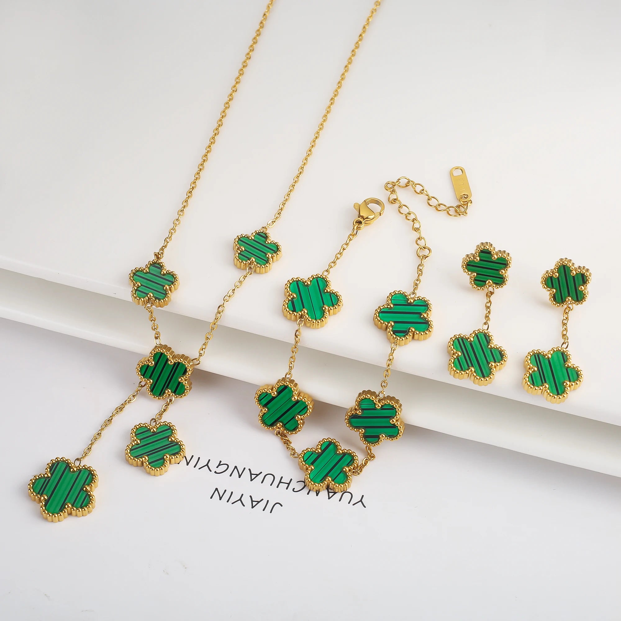 Three-piece clover jewelry set with green enamel five-leaf charms, gold tone necklace and earrings