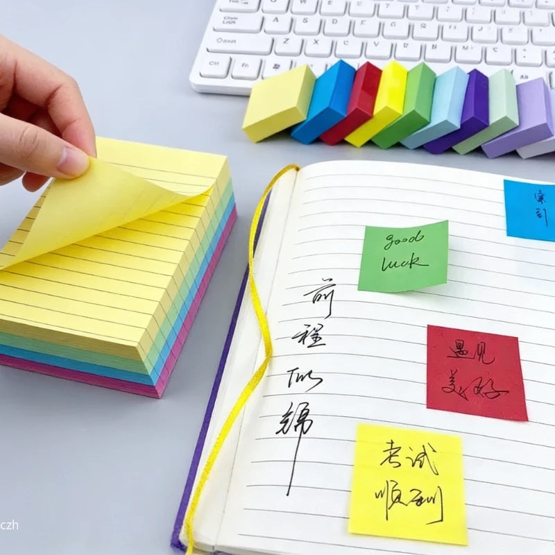 Hand placing yellow sticky notes in a lined memo book with multiple color flags.