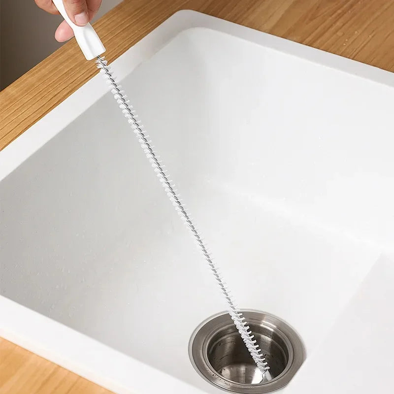 Flexible pipe cleaning brush with white handle and spiral bristles in kitchen sink drain