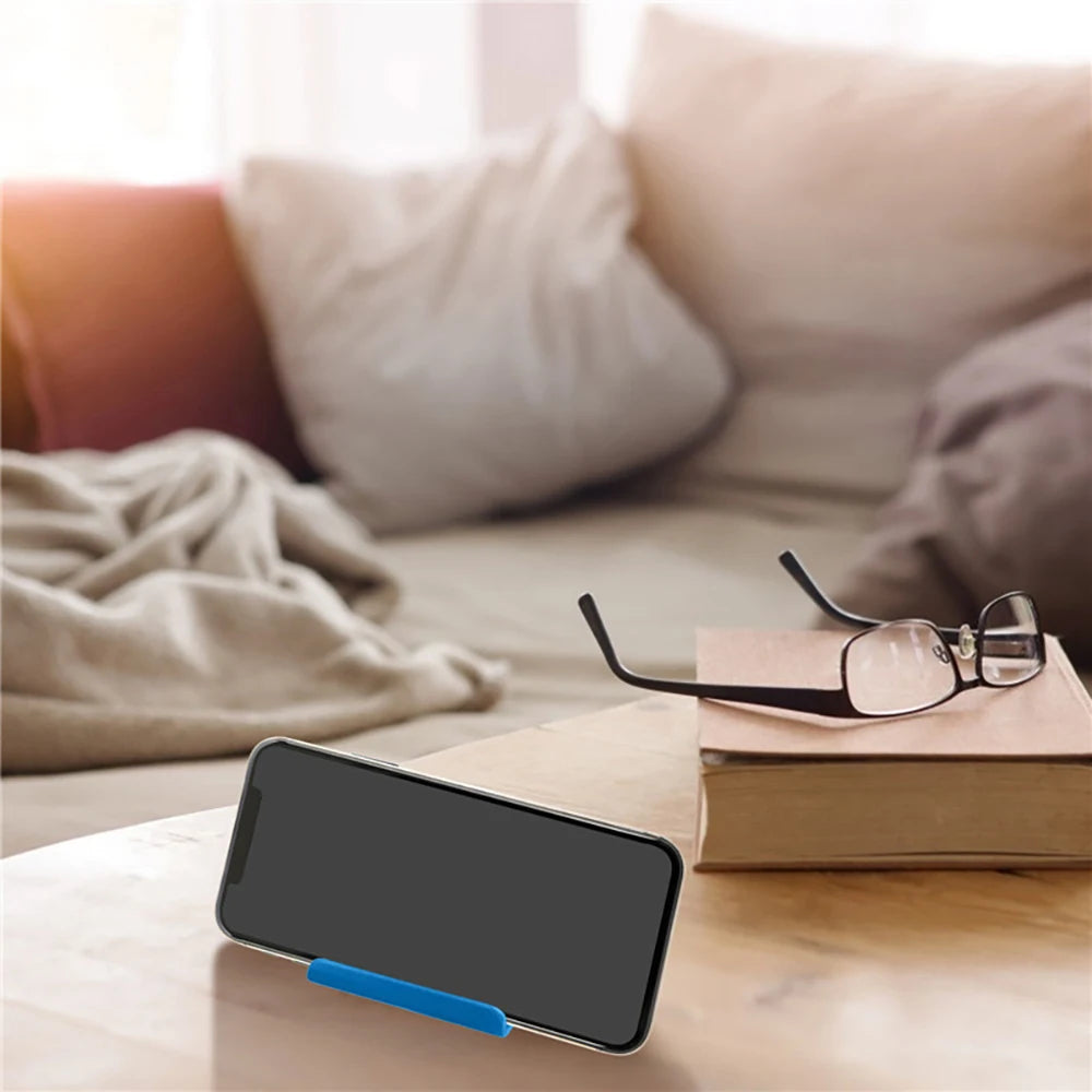 Black smartphone resting on a blue plastic phone holder stand on tabletop