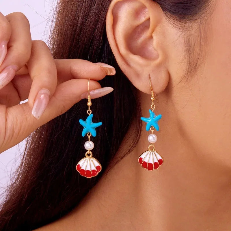 Gold hook earrings with blue starfish, red scallop shell, and pearl bead dangles