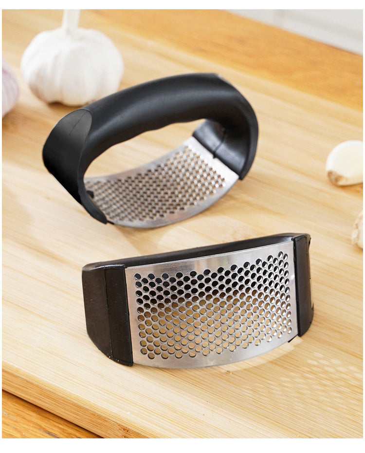 Manual garlic press resting on cutting board with perforated metal grater
