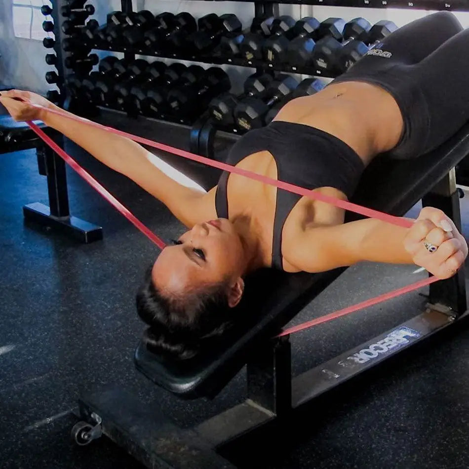 Red and black resistance loop bands stretched across legs during floor exercise