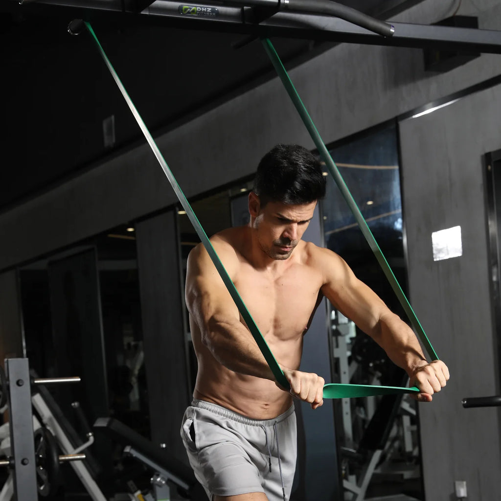 Green resistance loop band for upper-body training, held with hands during squats